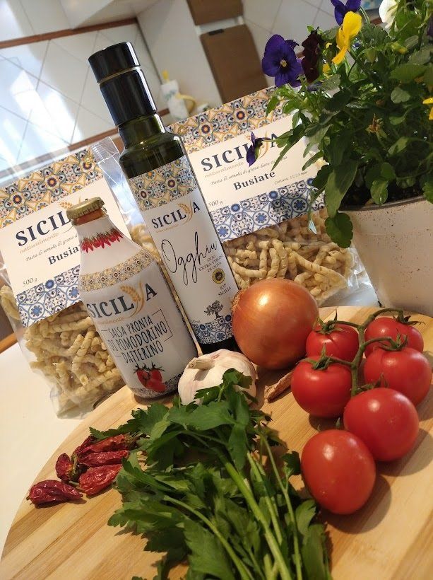 Due confezioni di Busiate sul tavolo con olio, salsa di datterino, aglio e pomodori